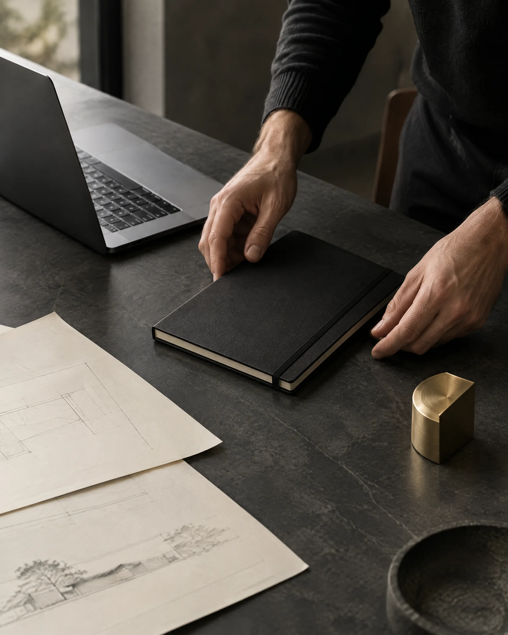 Business owner organising a notebook and plans beside a laptop